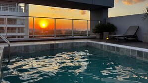 Ein Dachpool mit Sonnenuntergangsblick, eine Liege und ein Topfpflanze.