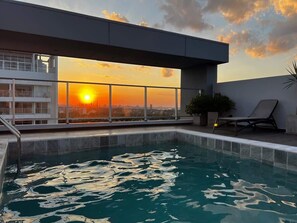 A rooftop pool with a sunset view, a lounge chair, and a potted plant. - Corporate Stays Unico - 1405  (Asunción)