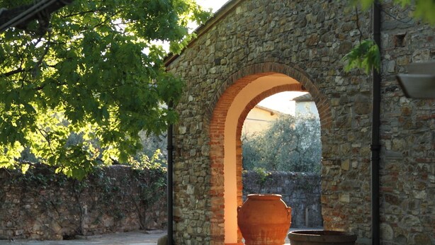 An outdoor stone archway with a large terracotta pot in the foreground. - Podere Fichereto: Stone House, Olive Grove, and Parking for Family and Friends (Scandicci)