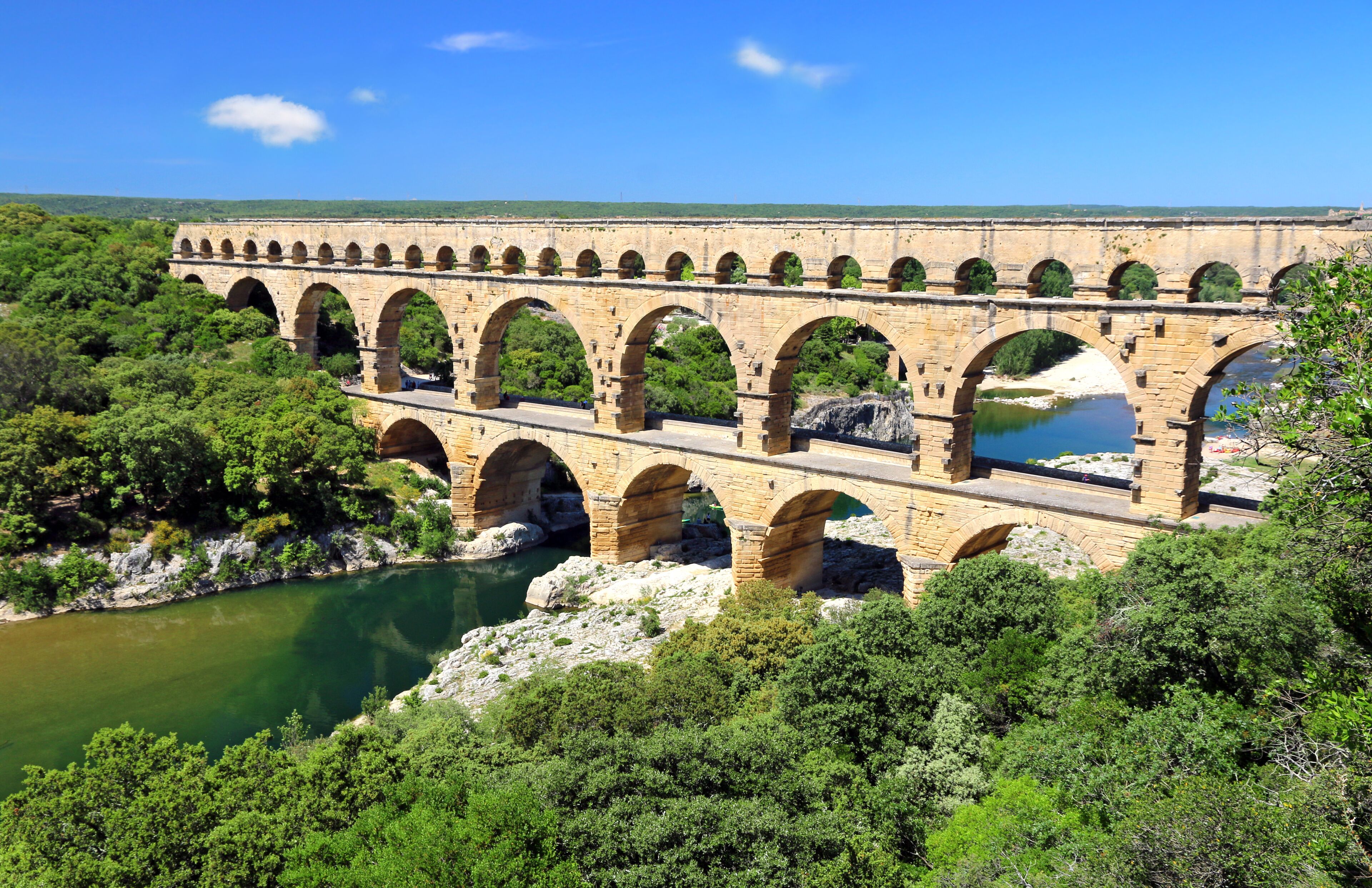 Un puente de piedra con varios arcos sobre un río, rodeado de vegetación.