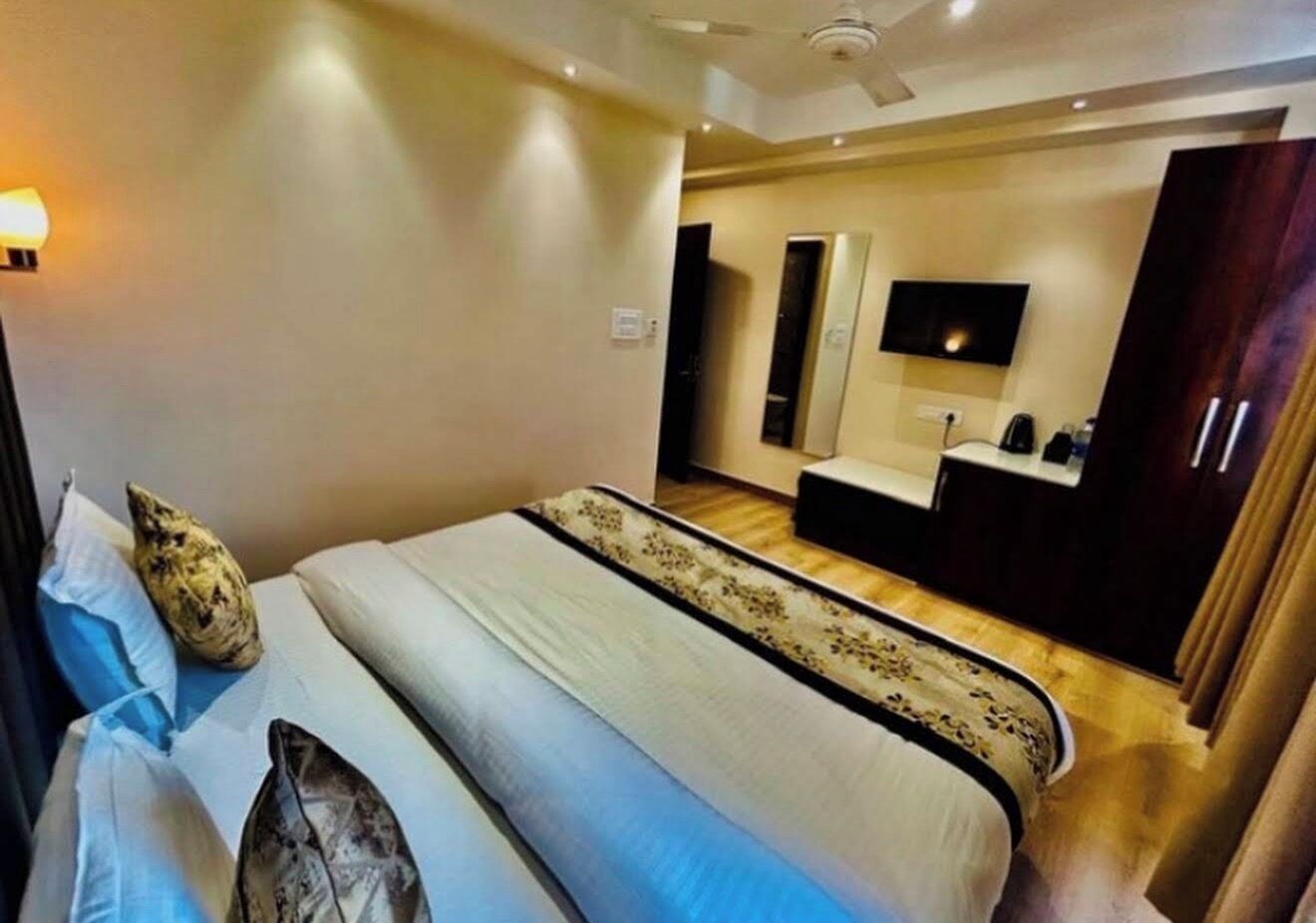 Een hotelkamer met een bed, nachtkastjes, een spiegel, een televisie en een kledingkast.