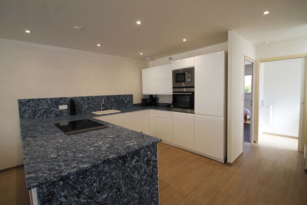 A modern kitchen with white cabinets, a black microwave, and a granite countertop.