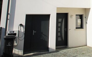 A building with two black doors, a small window, and a recycling bin.