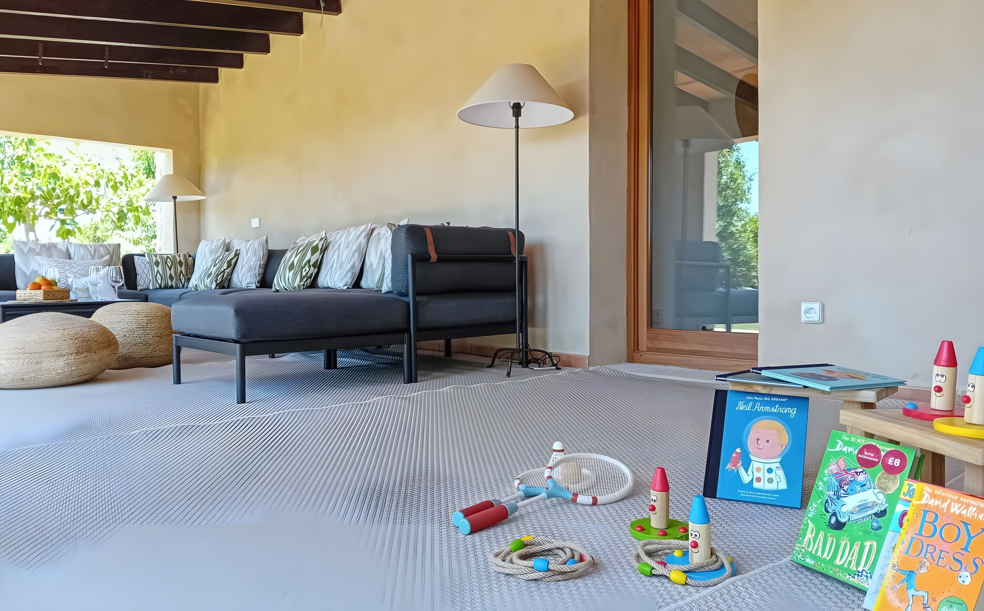Een moderne woonkamer met een bank, een lamp en kinderspeelgoed.