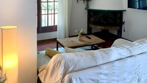 A bedroom with a bed, a TV, a fireplace, a window with curtains, and a lamp. - Country House Near Ciutadella with Private Pool, Shared Terrace, and Wi-Fi (Ciutadella)