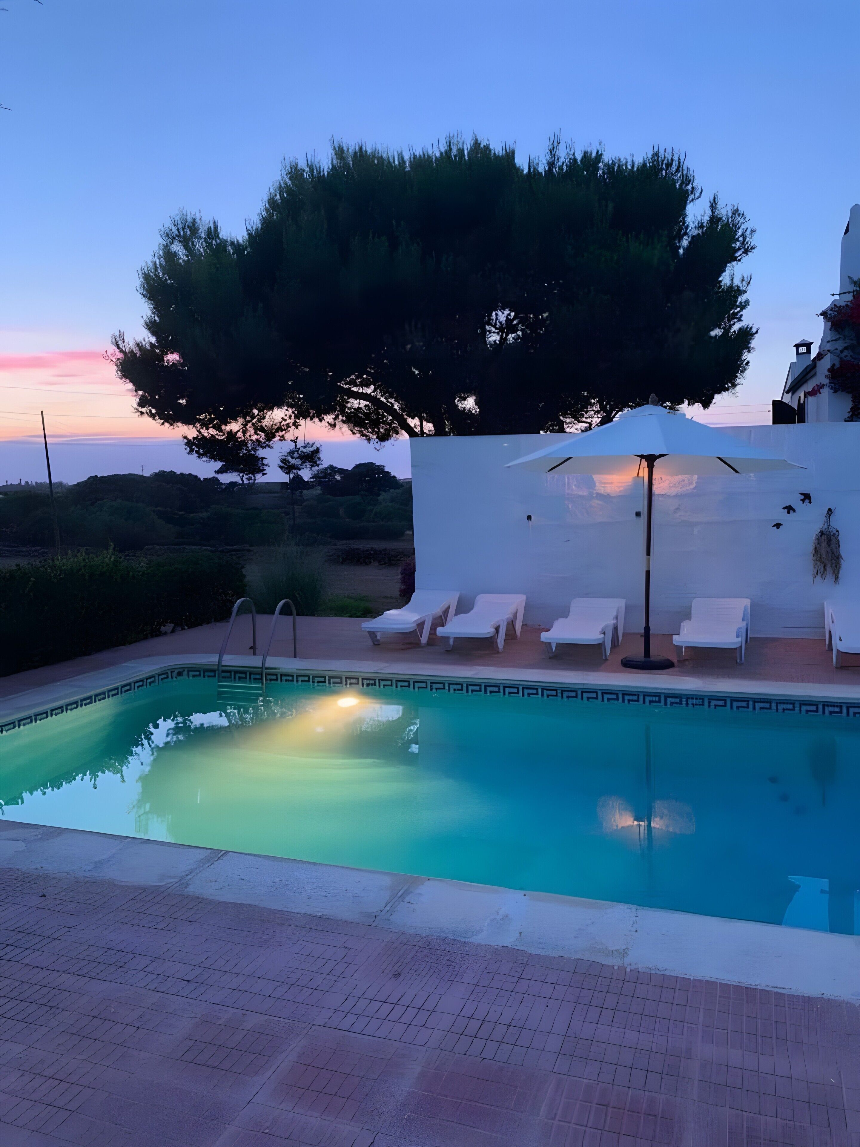 A swimming pool with lounge chairs and a white wall in the background.