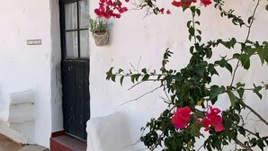A white building with a black door, a small potted plant, and a sign above the door. - Country House Near Ciutadella with Private Pool, Shared Terrace, and Wi-Fi (Ciutadella)