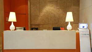 Una mesa de recepción con dos lámparas, un monitor de computadora y una pequeña bandera.
