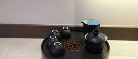 A black, round, modern table with a central decorative pattern, surrounded by four black vases and a black pitcher.