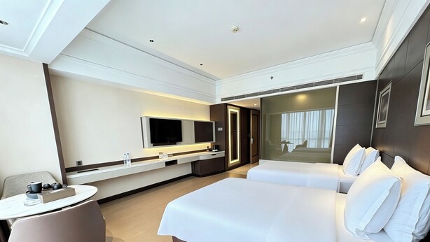 A modern hotel room with a large bed, a desk, a chair, and a television. - Jinjiang Shiji Fliport Hotel (Quanzhou)