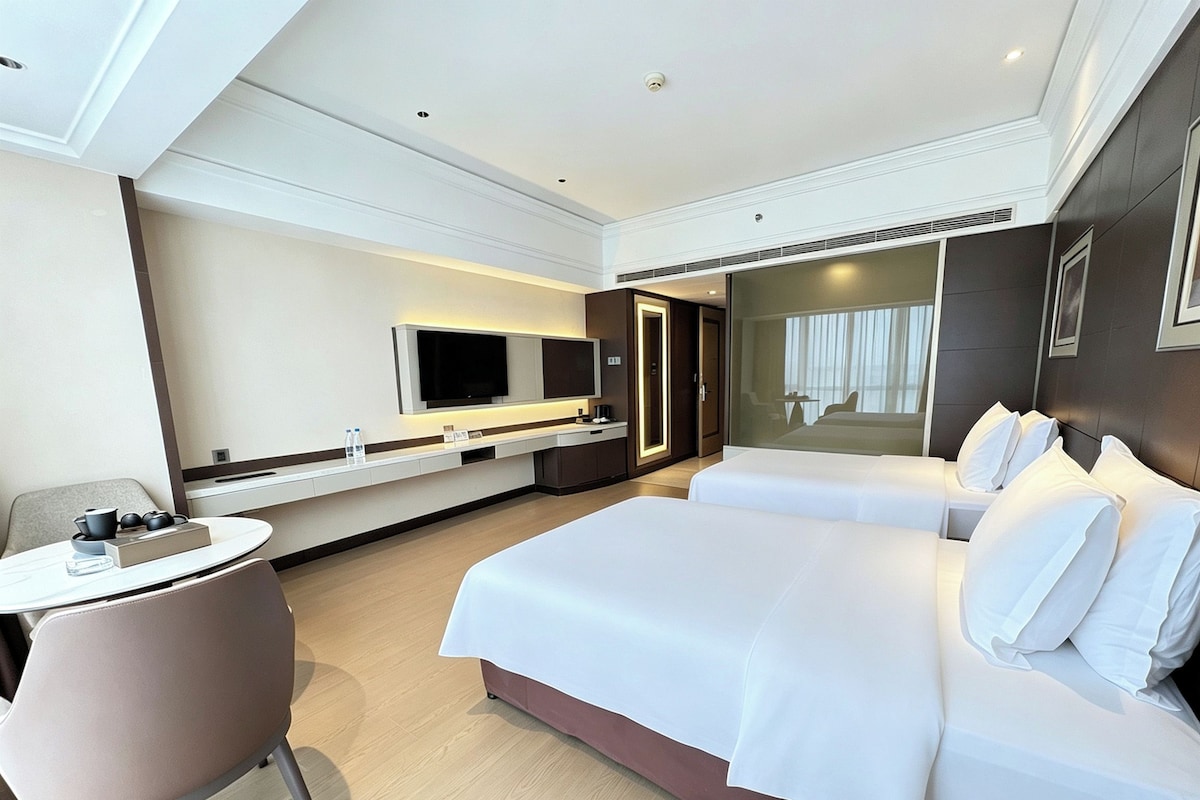 Une chambre d’hôtel moderne équipée d’un grand lit, d’un bureau, d’une chaise et d’un téléviseur.