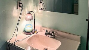 Een badkamer met een wastafel, spiegel en een wandlamp.