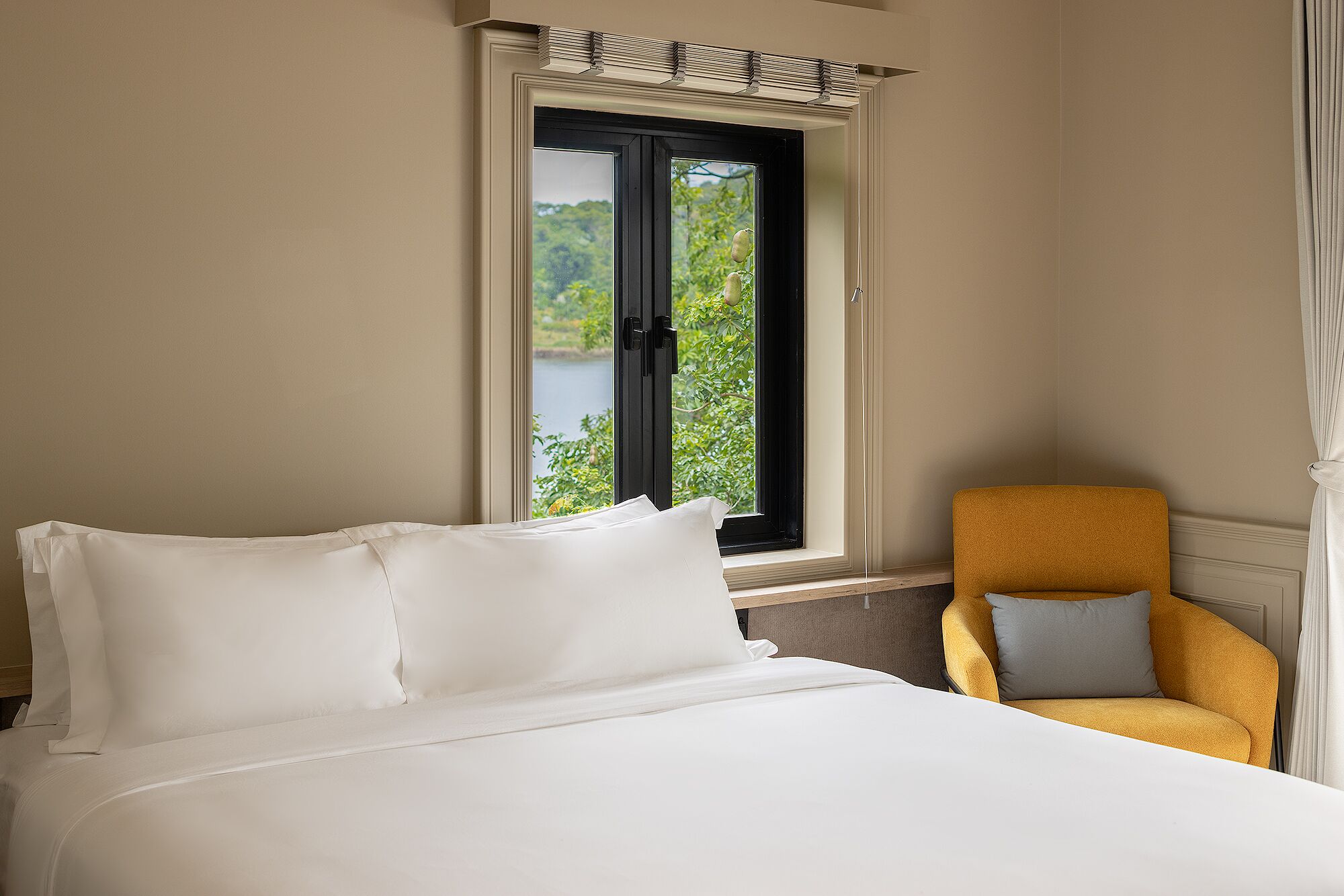 A room with a bed, a chair, and a window with a view of greenery.