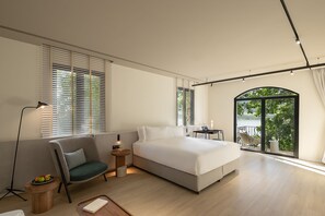 A modern bedroom with a bed, a chair, a desk, and a view of the outdoors.