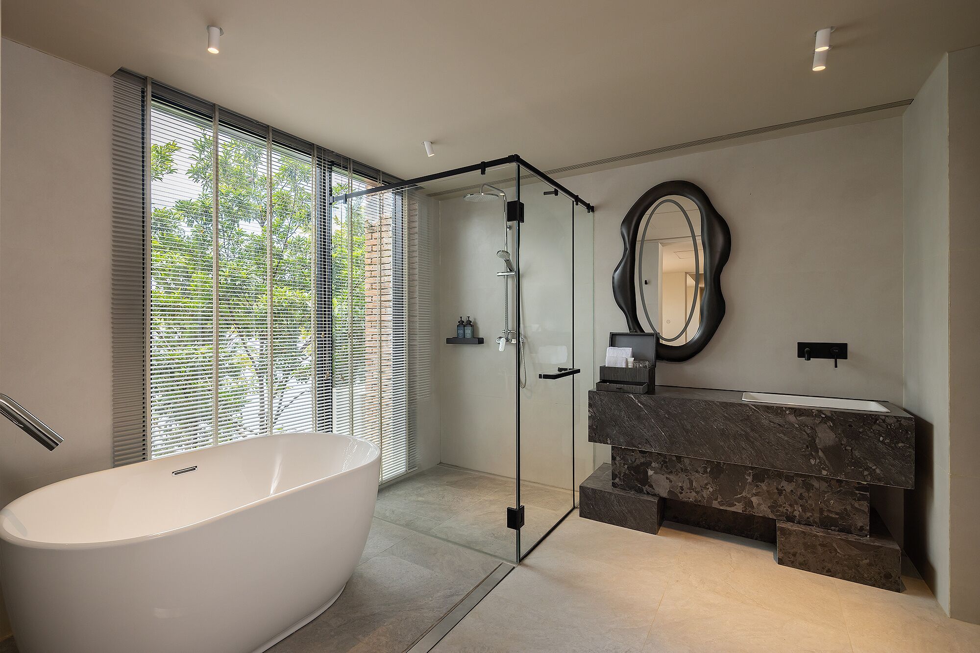 A modern bathroom with a freestanding bathtub, a glass-enclosed shower, and a marble vanity.