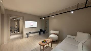 Una sala moderna con un televisor de pantalla plana, un sofá, una mesa de centro y una lámpara.