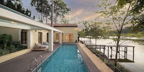 Une piscine avec une terrasse en bois, des chaises longues et une vue sur un lac.
