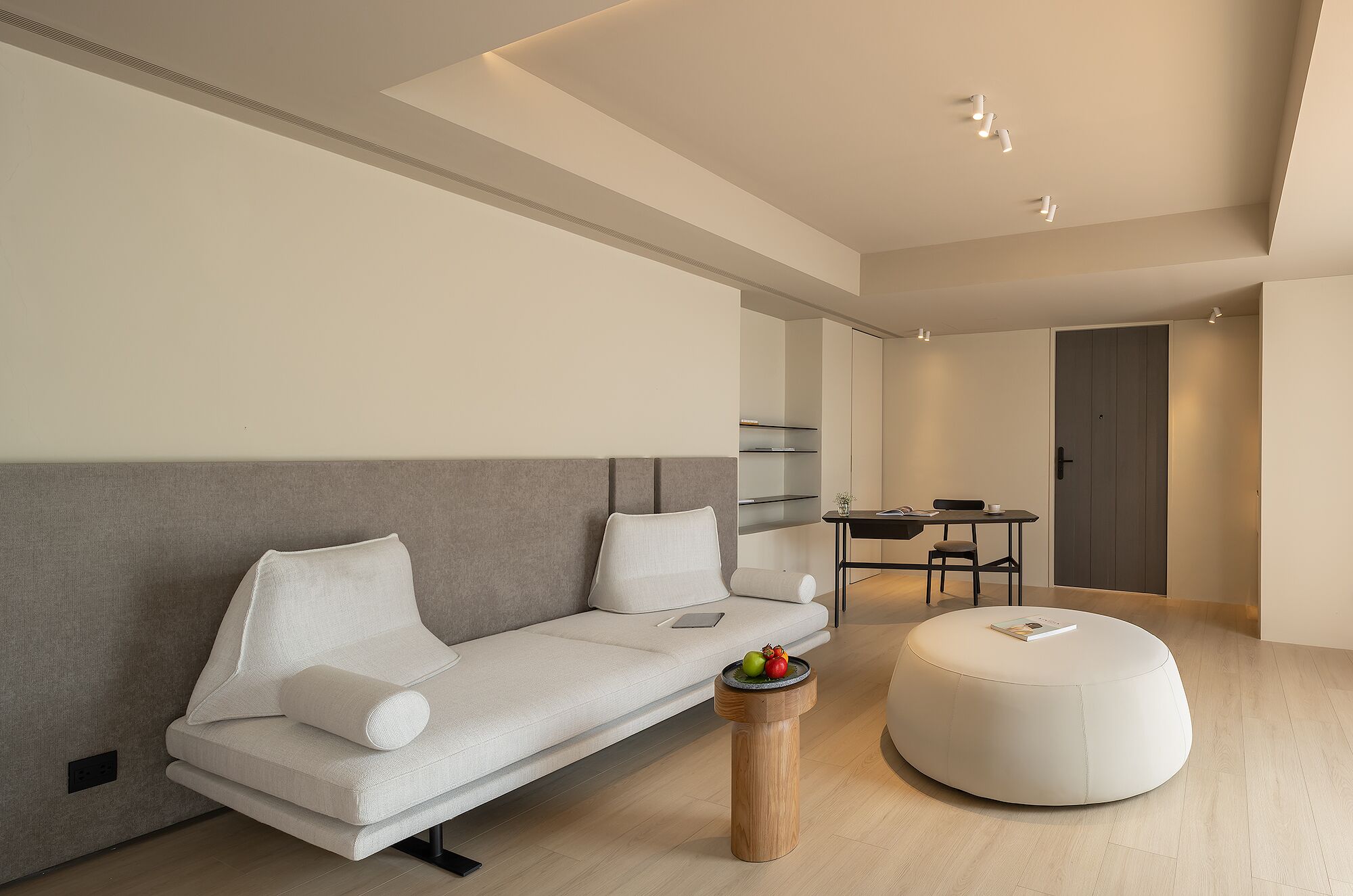 Una sala moderna con un sofá, un reposapiés y una mesita con fruta.