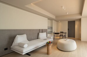Una sala moderna con un sofá, un reposapiés y una mesita con fruta.