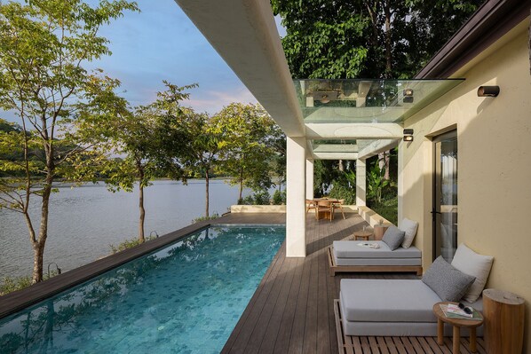 A poolside area with a glass balustrade, wooden deck, and seating. - U Khao Chi Chan Pattaya (Sattahip)