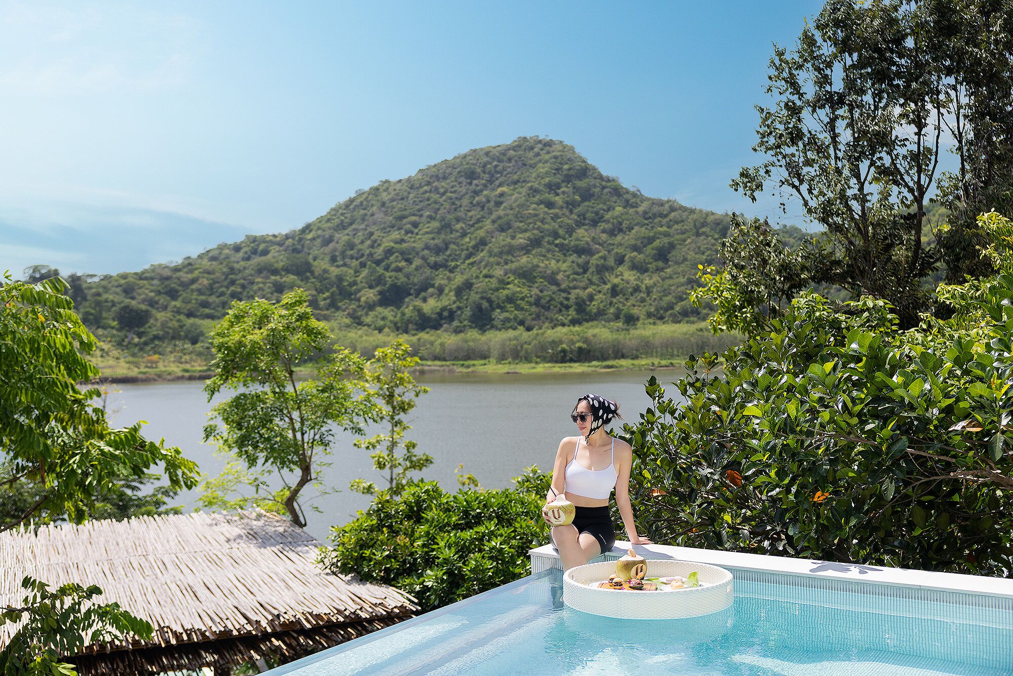 Una persona sentada junto a una piscina con vistas a la montaña.