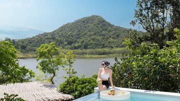 Una persona sentada junto a una piscina con vistas a la montaña.