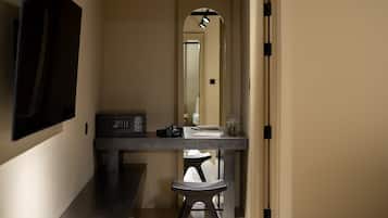 A hallway with a dark wooden bench, a small table with a microwave, and a mirror reflecting a door and a light fixture.
