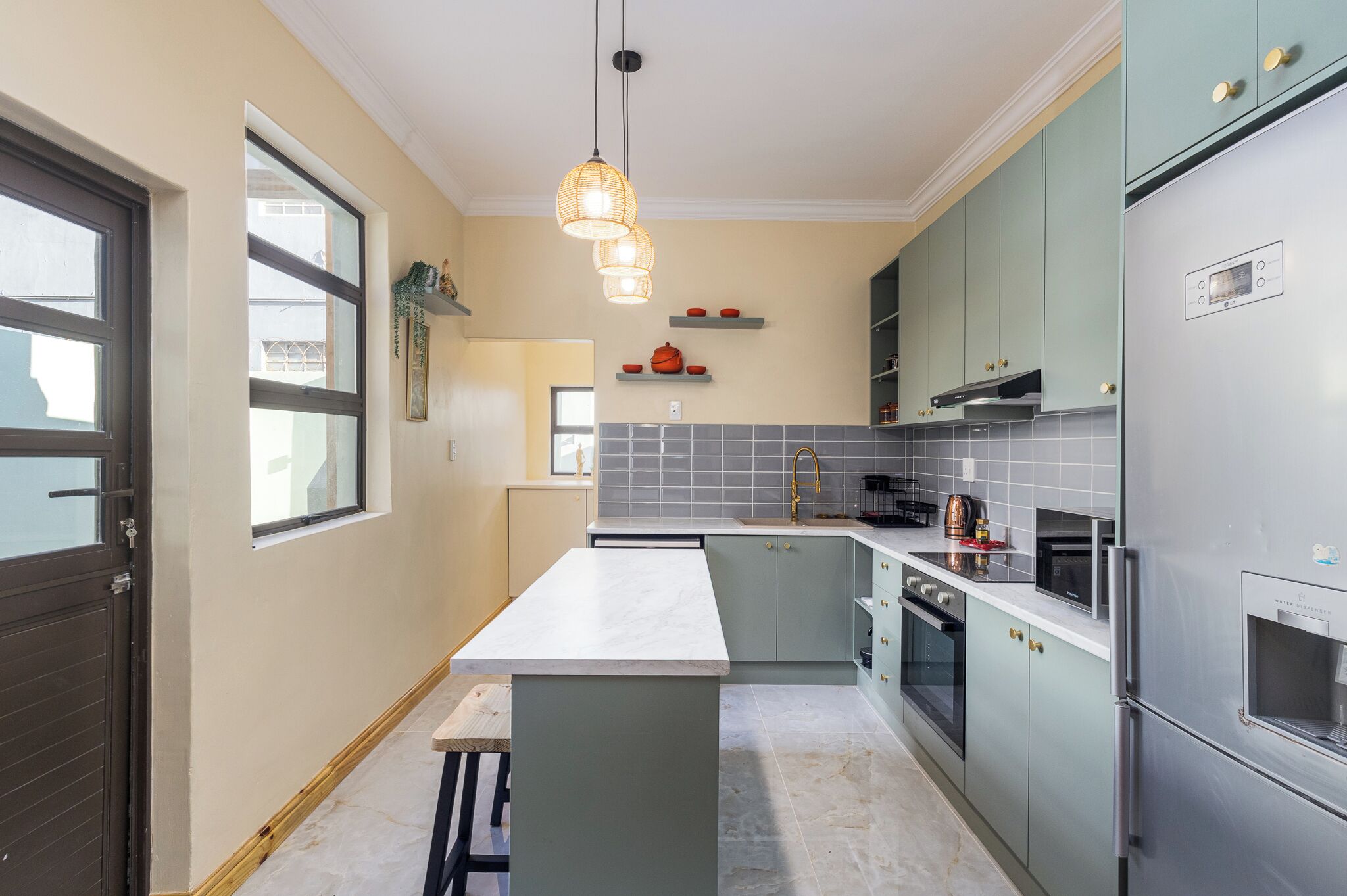 A modern kitchen with a central island, built-in appliances, and a window.