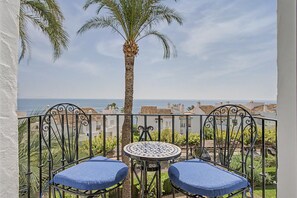 A balcony with two chairs and a table, overlooking a coastal town and the sea. - Apartment 'Vista Azul' with Sea View, Wi-Fi and Air Conditioning (La Herradura)