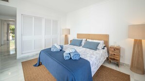 Ein Schlafzimmer mit einem Bett, Nachttischen, Lampen und einem großen Fenster.