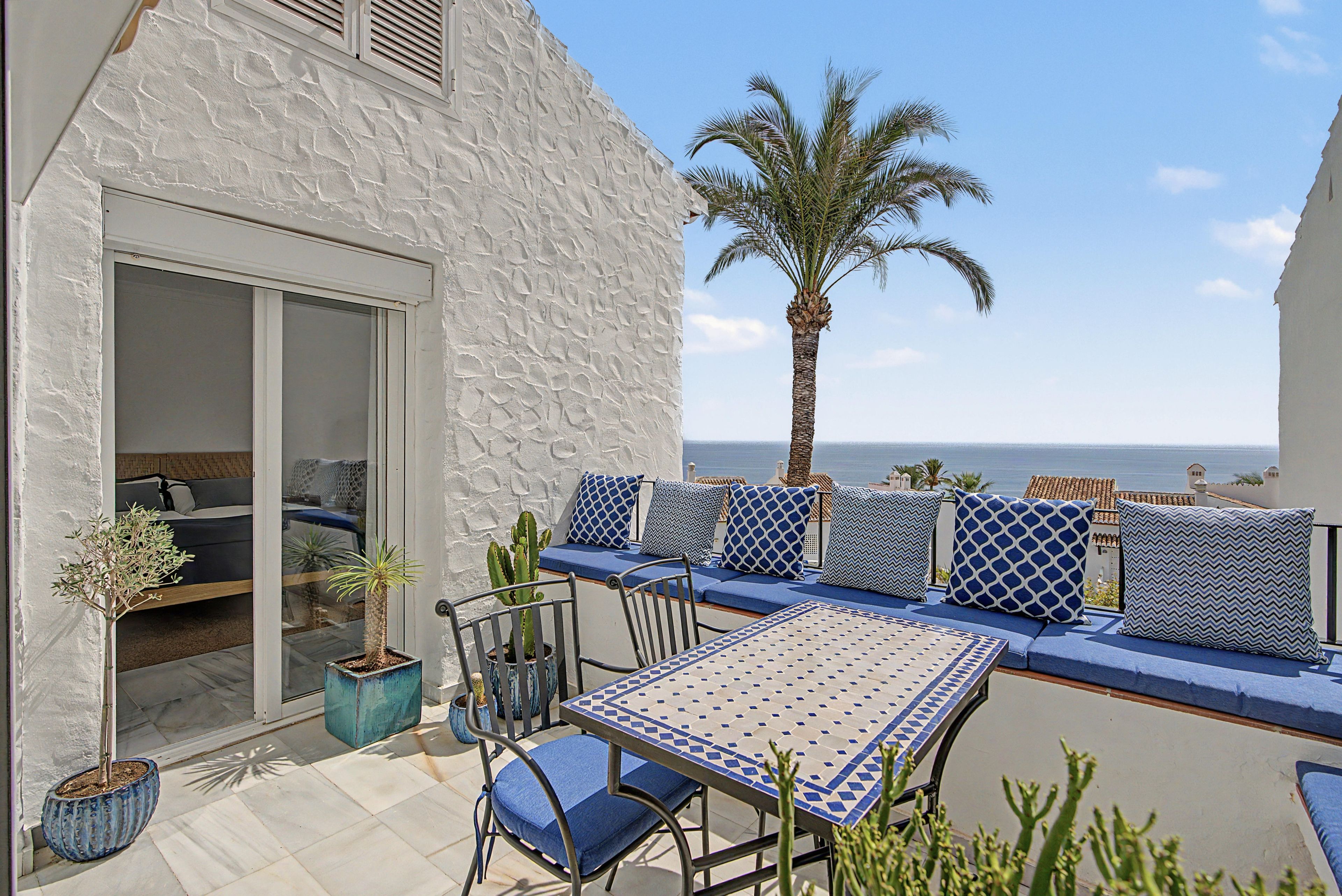 Eine Terrasse mit Sitzgelegenheit, einem Tisch und Blumentöpfen.