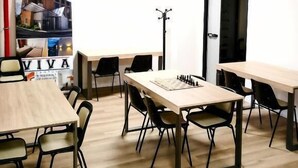 A room with multiple tables and chairs, a coat rack, and a door with an emergency exit sign. - VIVA CAMPUS (Ferrazzano)