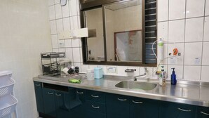 A kitchen with a stainless steel sink, a mirror above the counter, and various kitchen utensils and appliances.