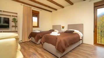 Une chambre d’hôtel avec deux lits, une télévision, un canapé et une fenêtre donnant sur un paysage agréable.
