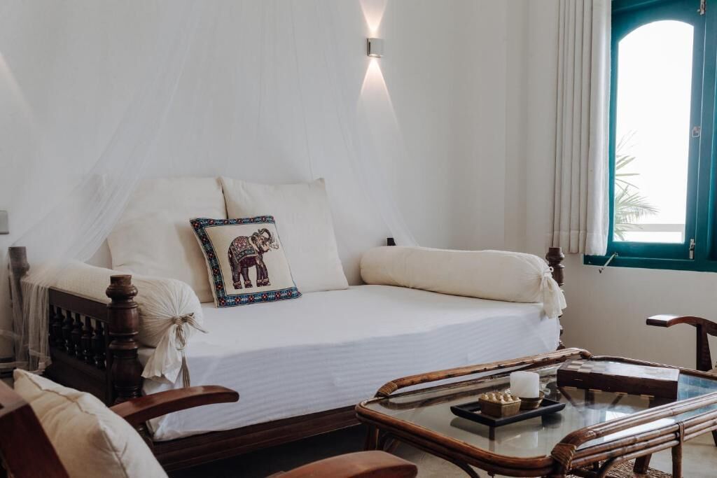 A bedroom with a bed, a bedside table, a chair, and a window with curtains.