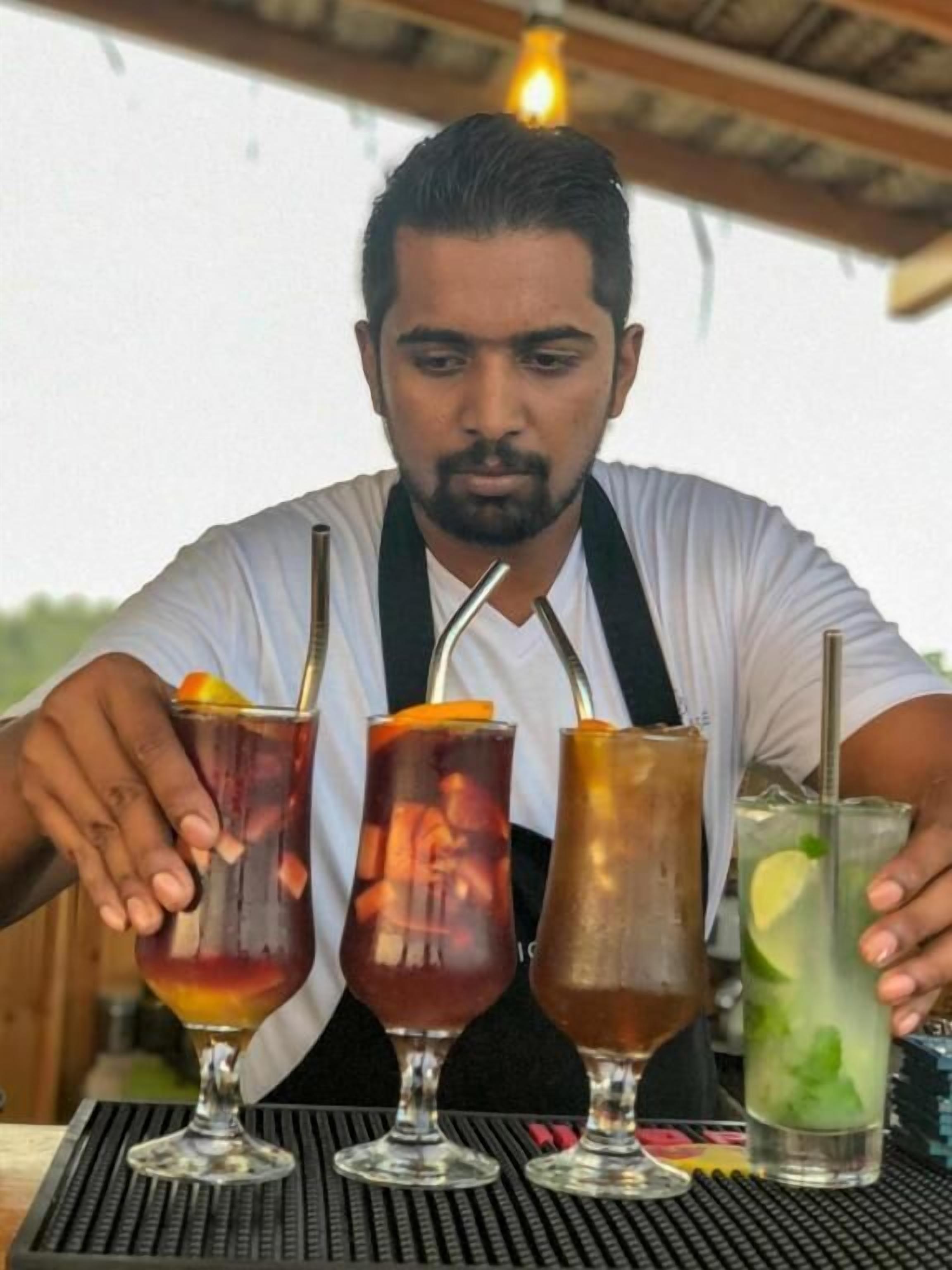 A person serving drinks at a bar with three different beverages.