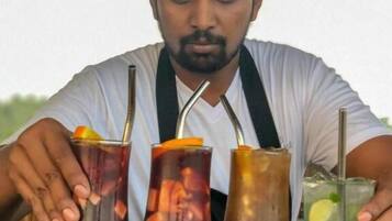 A person serving drinks at a bar with three different beverages.
