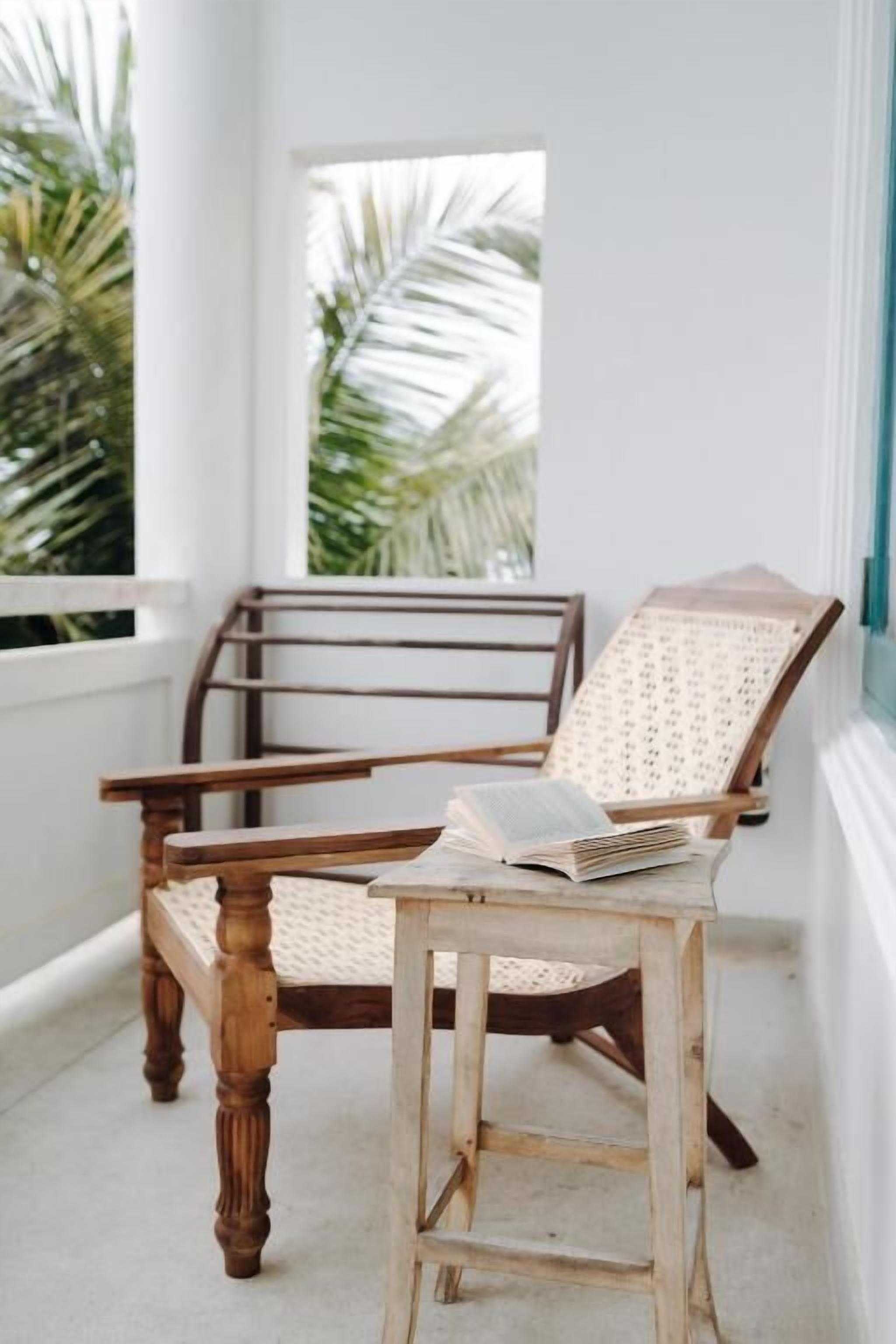 A wooden chair with a cushion, a small table, and a book on the table.