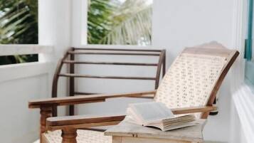 A wooden chair with a cushion, a small table, and a book on the table.
