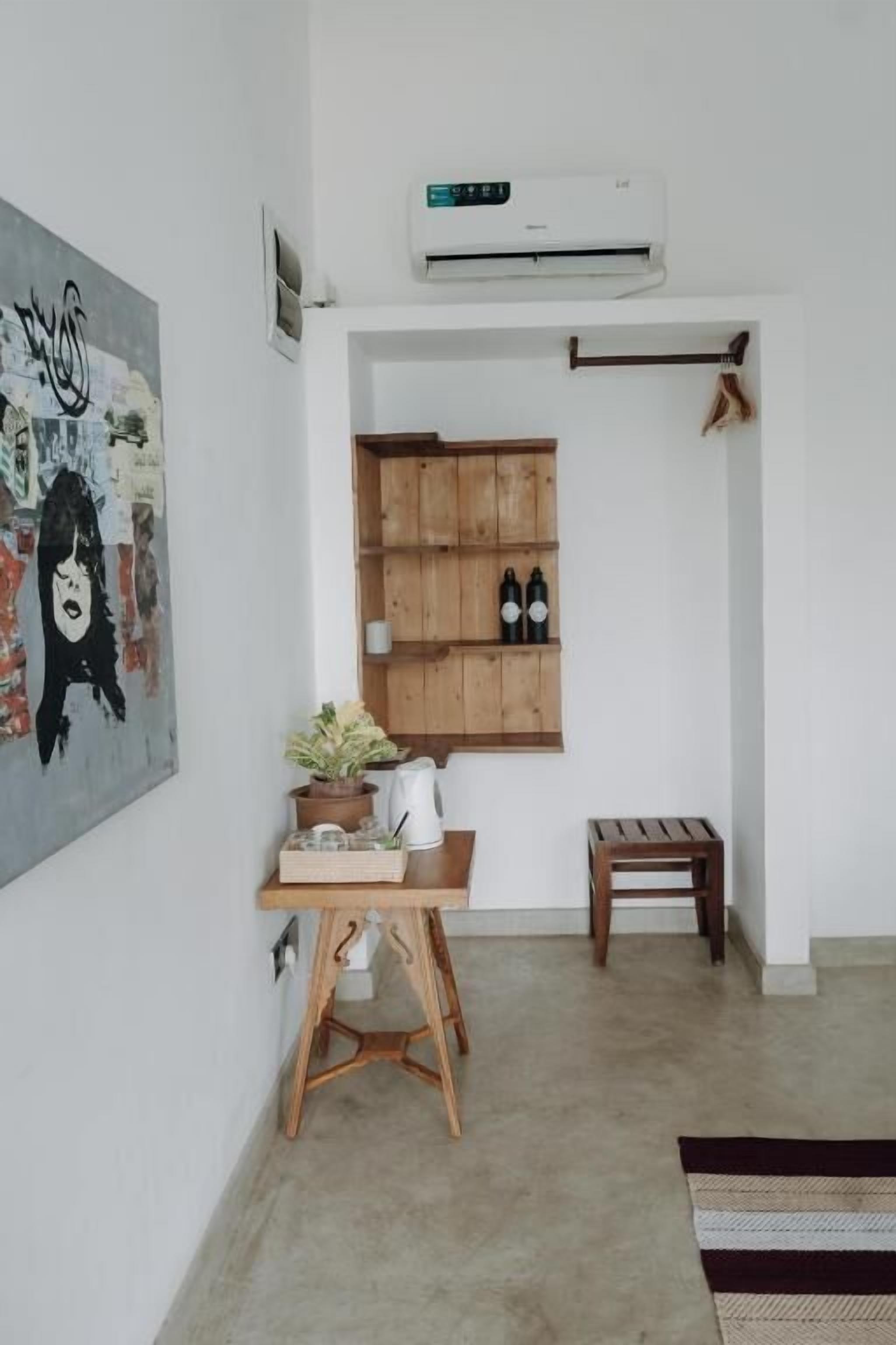 Une pièce avec un meuble en bois, une petite table sur laquelle est posée une plante, et un appareil de climatisation fixé au mur.