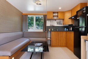 Eine moderne Küche mit Holzausstattung, einem schwarzen Kühlschrank und einem Fenster mit Blick auf Grünflächen.
