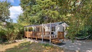 Eine kleine Holzhütte mit einer Holzterrasse und einer Hängematte.