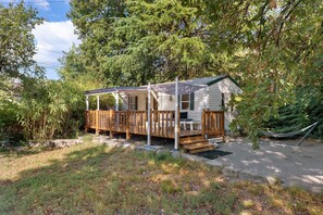 A small cabin with a wooden deck and a hammock. - Bungalow “L’échappée” with Mountain View, Wi-Fi, and Air Conditioning (Saint-Alban-Auriolles)