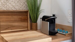Eine Küchenarbeitsplatte mit einer Kaffeemaschine, einem Holztablett und einem Blumentopf.