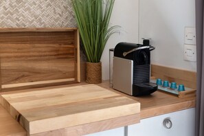 A kitchen counter with a coffee machine, a wooden tray, and a potted plant. - Bungalow “L’échappée” with Mountain View, Wi-Fi, and Air Conditioning (Saint-Alban-Auriolles)