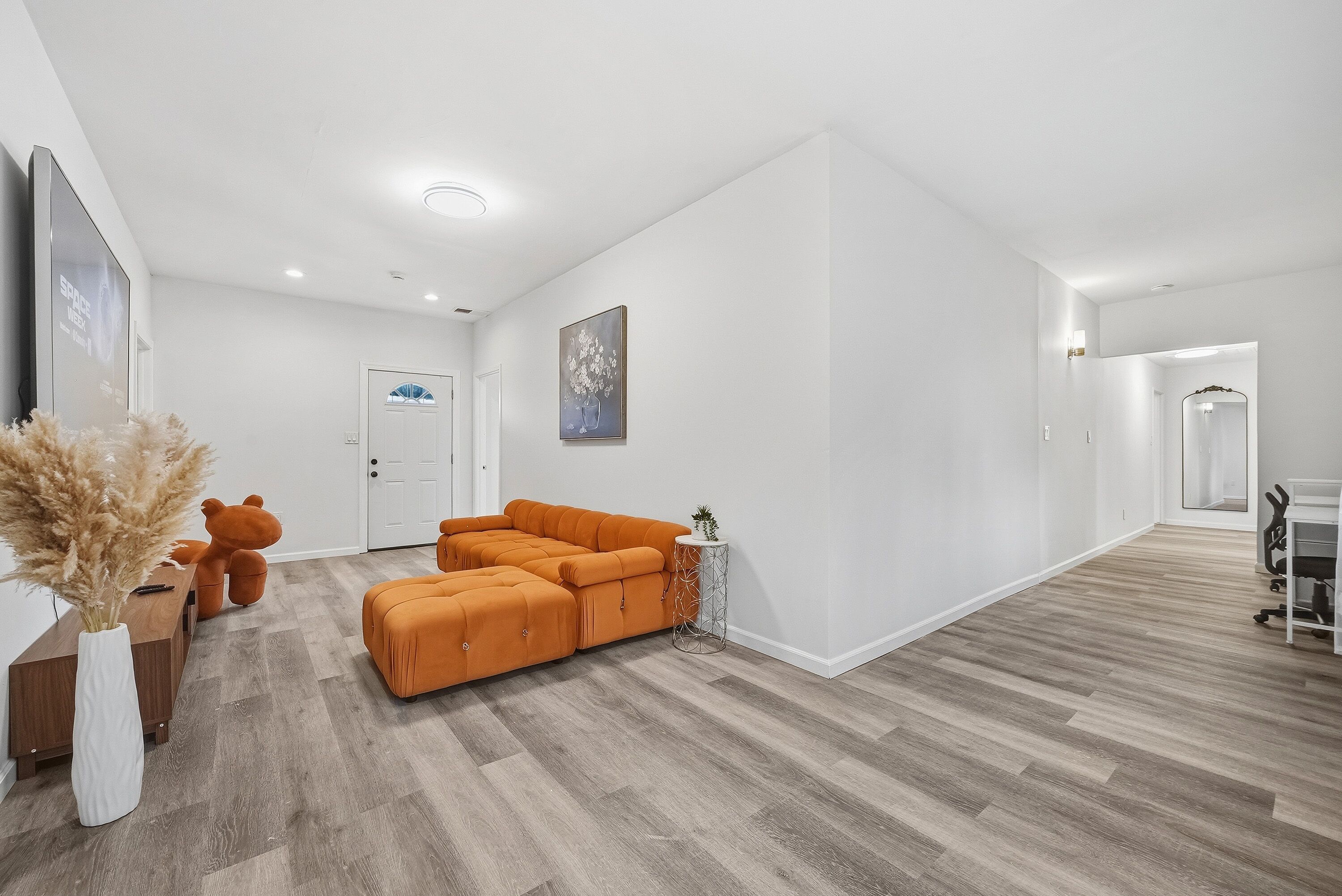 A spacious living area with a sectional sofa, a small side table with a plant, and a decorative vase.