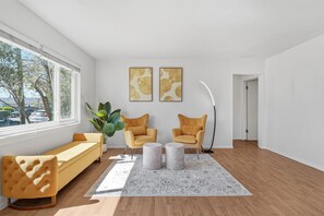 Ein modernes Wohnzimmer mit einer Couch, zwei Sesseln, einem Couchtisch und Kunstwerken an der Wand.