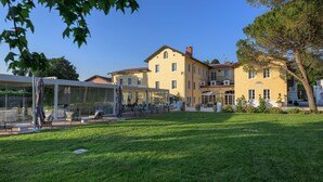 A large yellow building with a covered outdoor seating area and a well-maintained lawn.