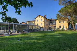 A large yellow building with a covered outdoor seating area and a well-maintained lawn. - Country House Villa Russiz  (Capriva del Friuli)