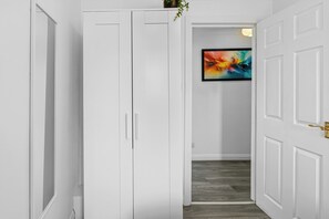 A hallway with white doors, a wooden floor, and a colorful abstract painting on the wall. - Prime location Pad/Free Parking/PS4/Wifi/Tourists (Salford)